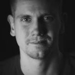 Black and white portrait of a pensive man looking directly at the camera.